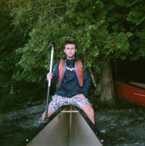 boy istting at the end of a canoe